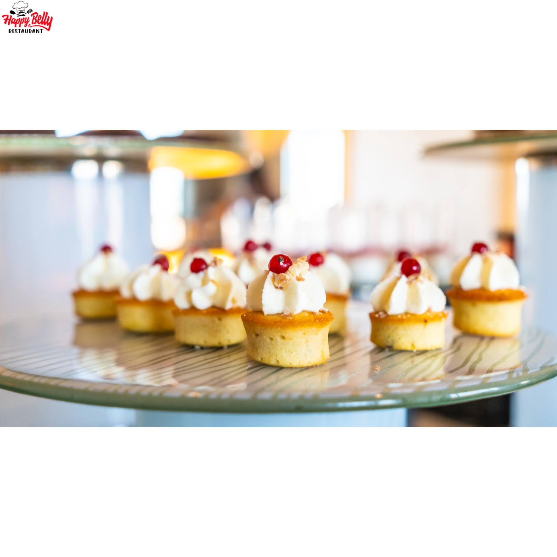 Mini sponge cakes topped with whipped cream and red berries on a glass platter.