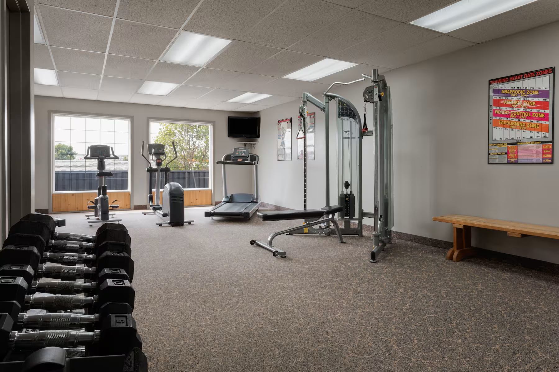 Fitness room with cardio machines, weights, and natural light at Travelodge Grande Prairie.