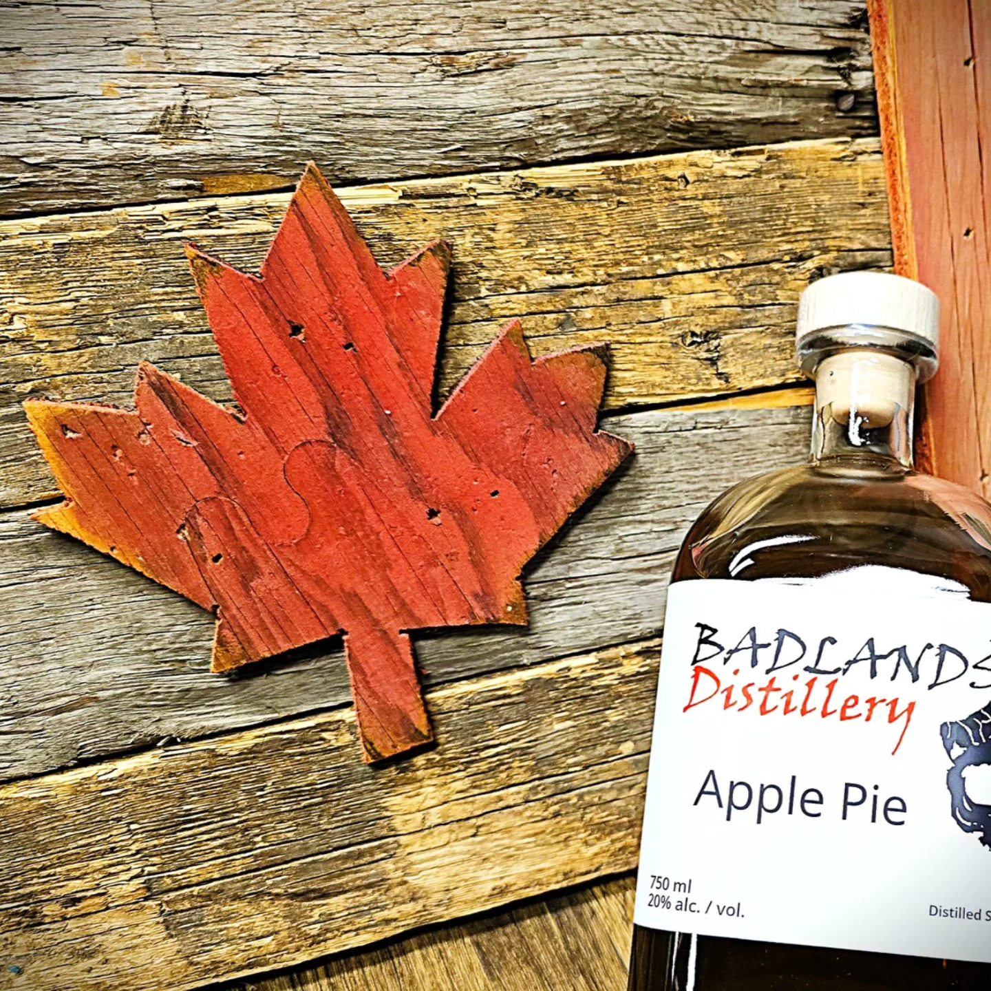 Badland Distillery Apple Pie distilled spirit with a maple leaf flag next to it.