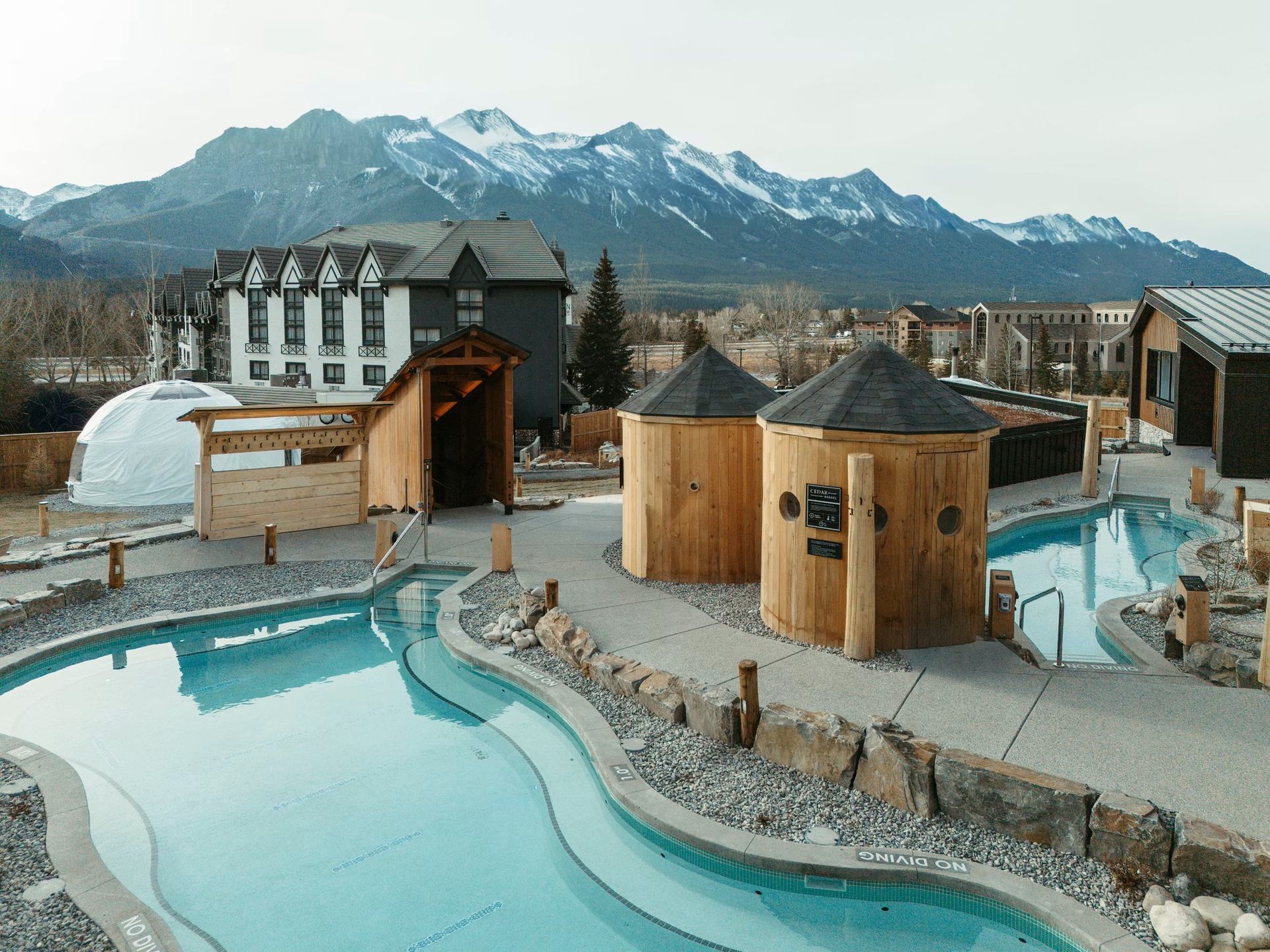 Outdoor Nordic spa pools with wooden saunas and mountain views at Everwild Canmore.