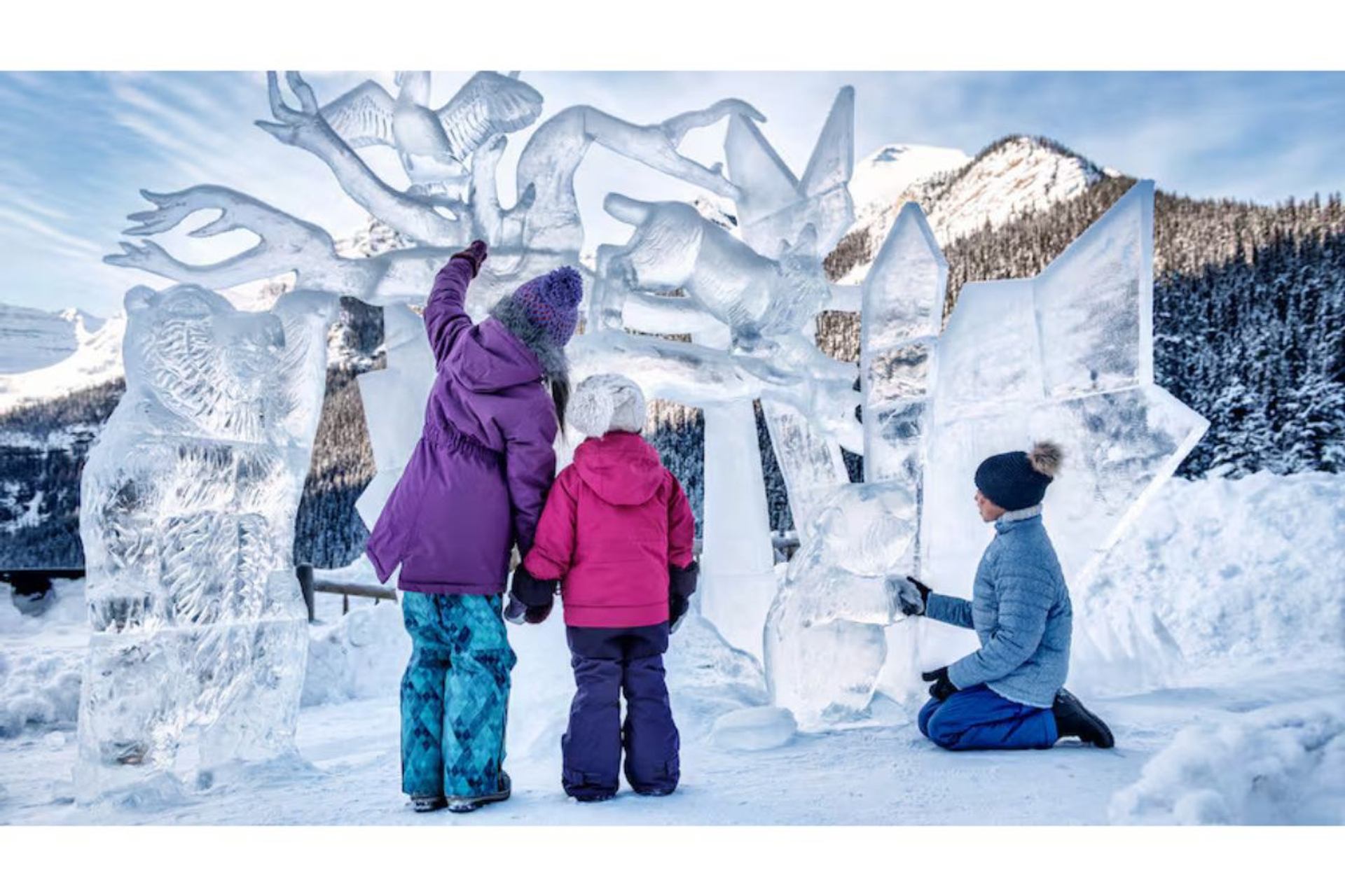 Three people admire intricate ice sculptures in a snowy mountain setting.