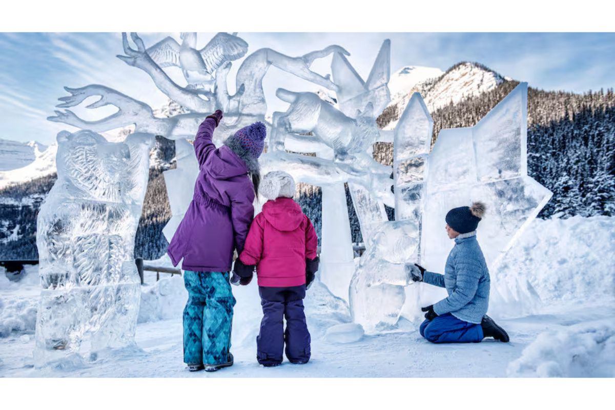 Three people admire intricate ice sculptures in a snowy mountain setting.