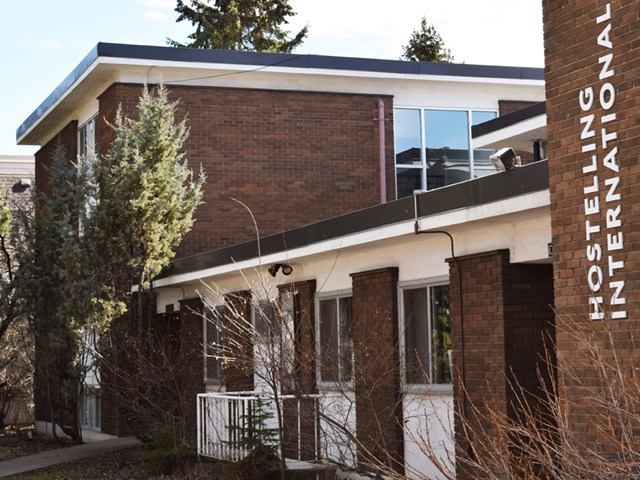 Brick building with sign and surrounding greenery.