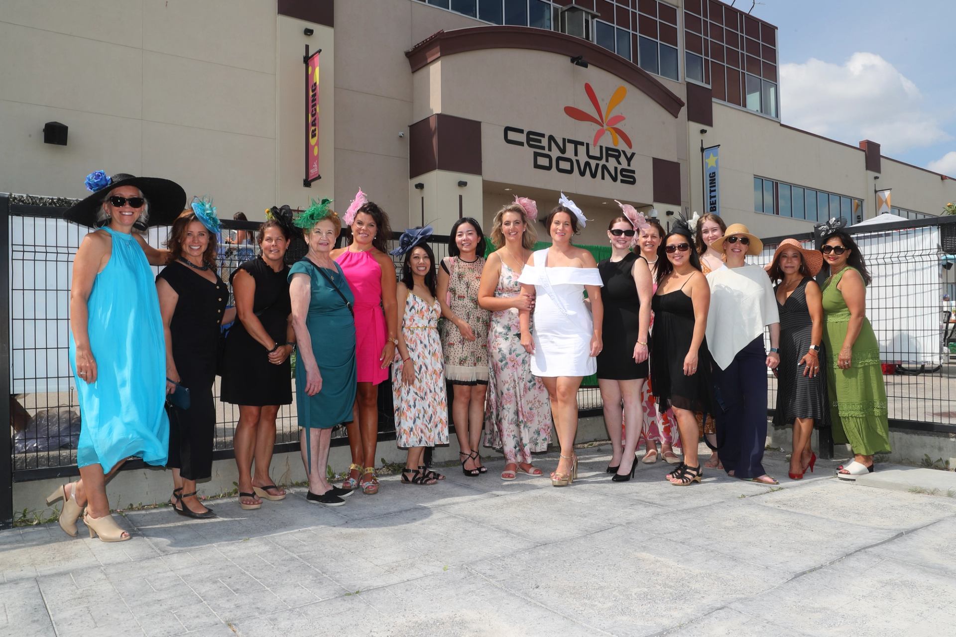 Group of people dressed up standing in front of Century Downs racetrack building.