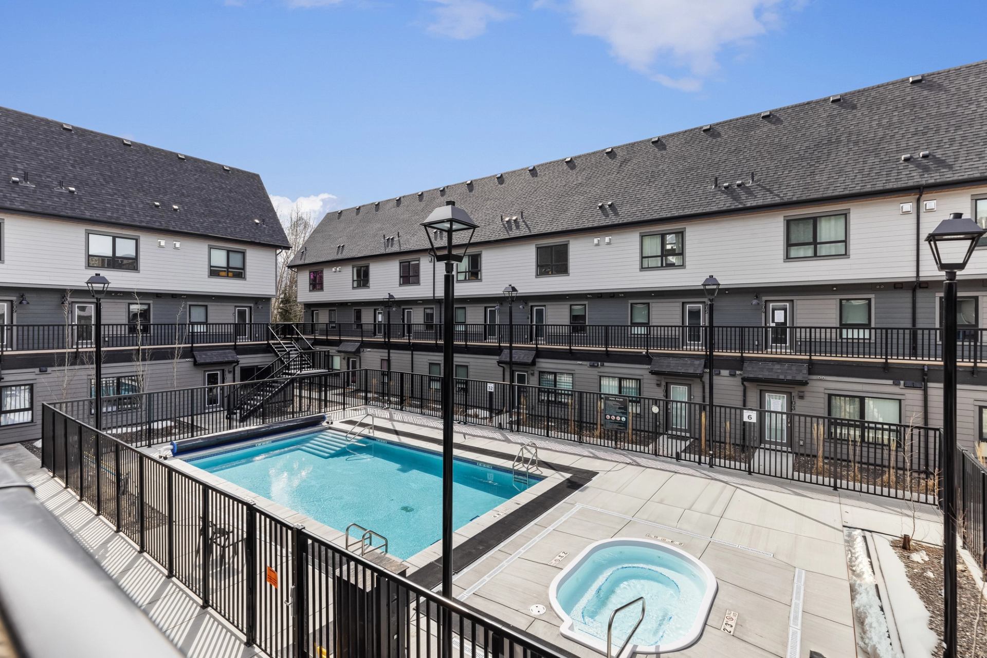 Fenced outdoor pool and hot tub in a townhouse courtyard.