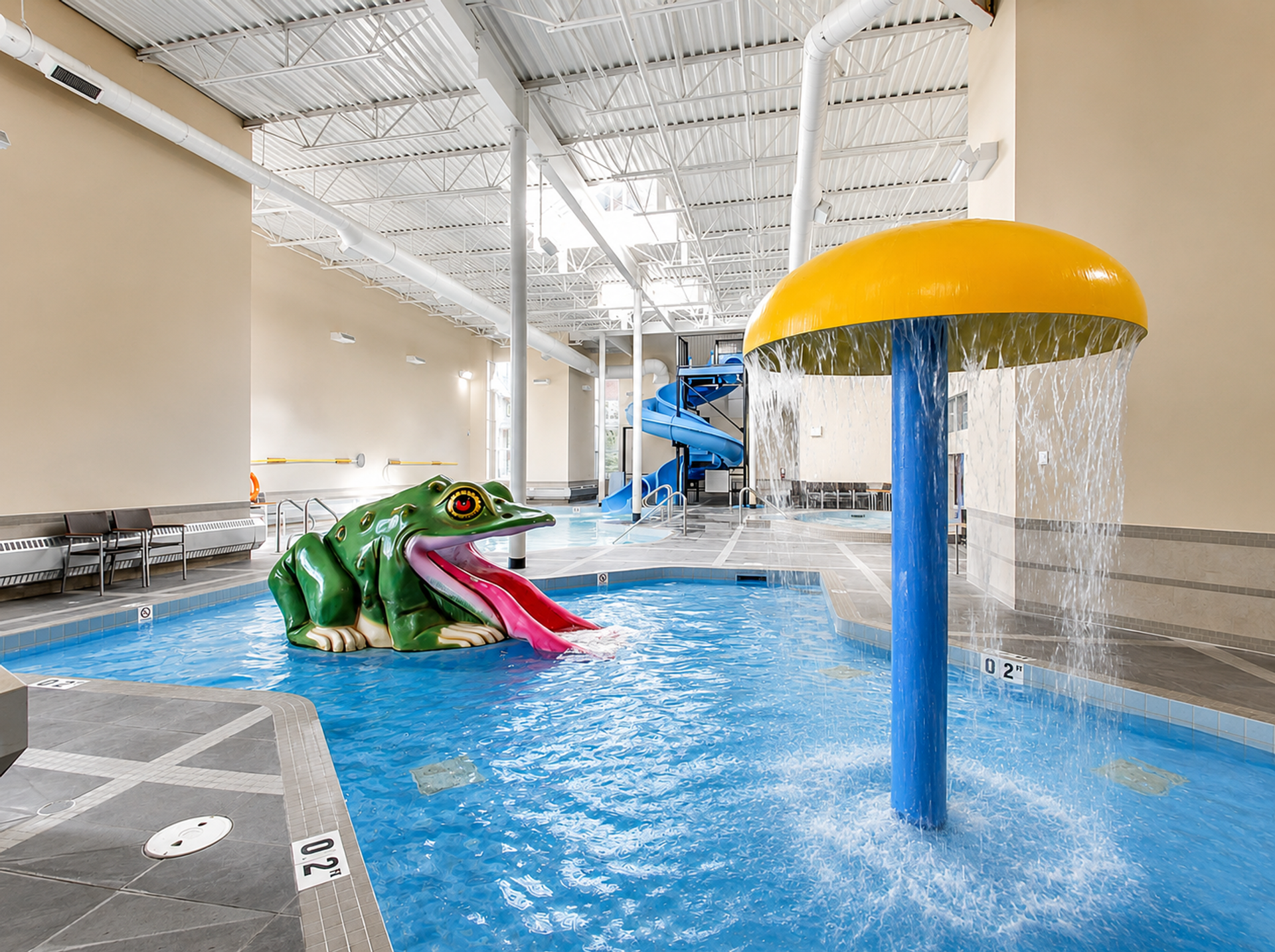 Indoor children's pool with frog slide, mushroom fountain and blue waterslide.