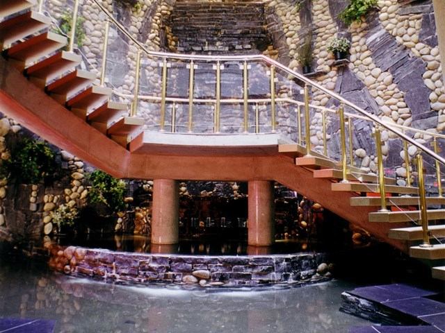 Curved staircase with golden railings around a water feature at Four Points by Sheraton.