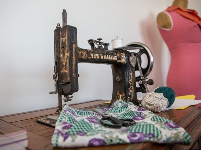 Vintage New Williams sewing machine on table with fabric, scissors, thread and dress form.