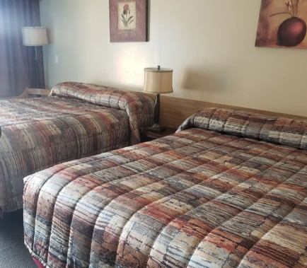 Guest room with two double beds, bedside lamp, and wall art.