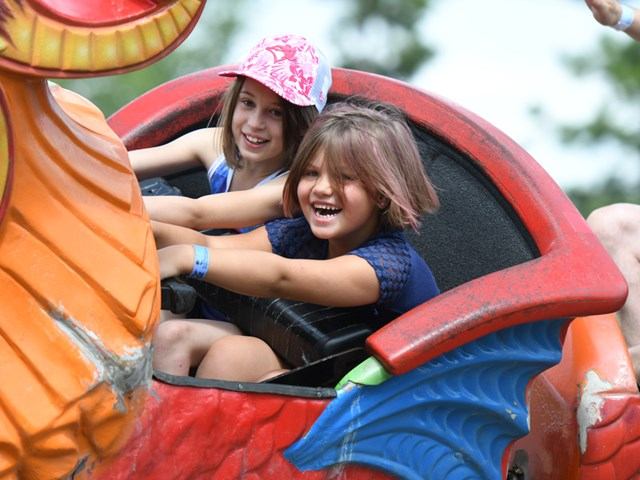Two kids ride a colorful amusement attraction at K Days festival.