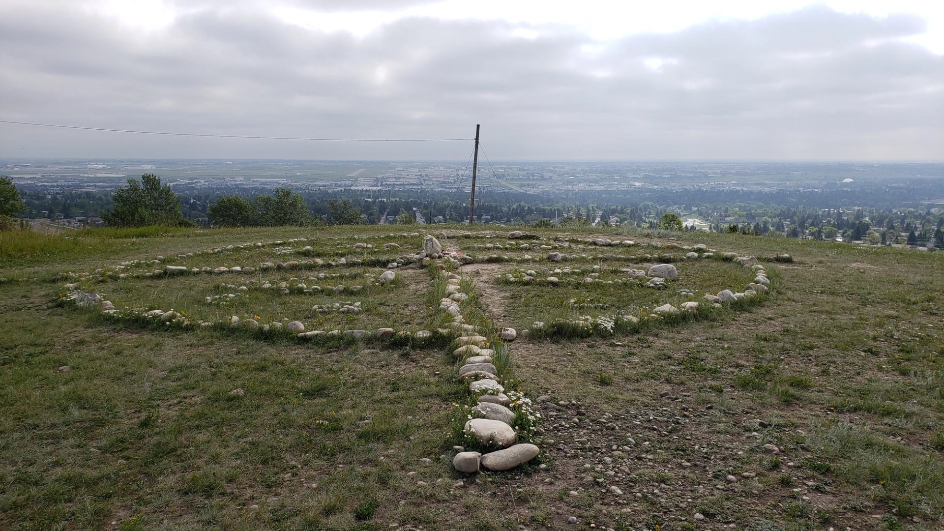 Stone circle of the Siksikaitsitapi Medicine Wheel with cityscape in the distance