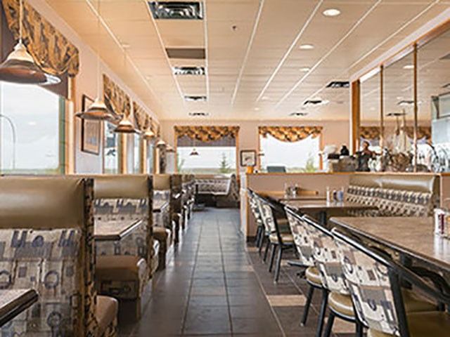 Bright diner-style restaurant with patterned booths and tables at Super 8 Drayton Valley.