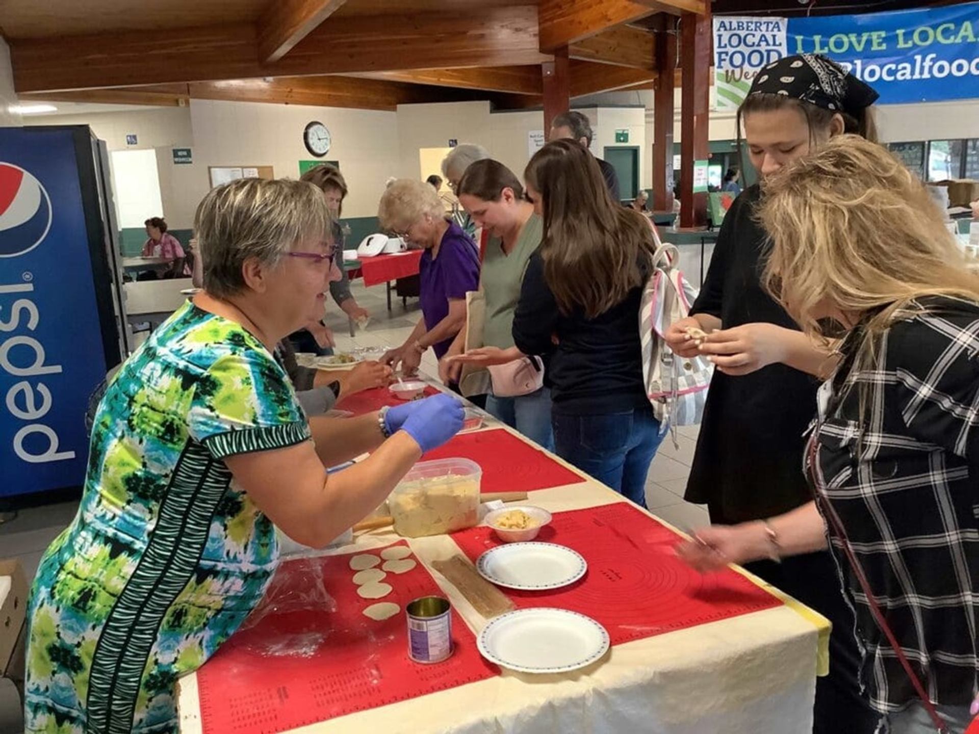 Community members gather at indoor tables, preparing food together during Alberta Local Food Week.