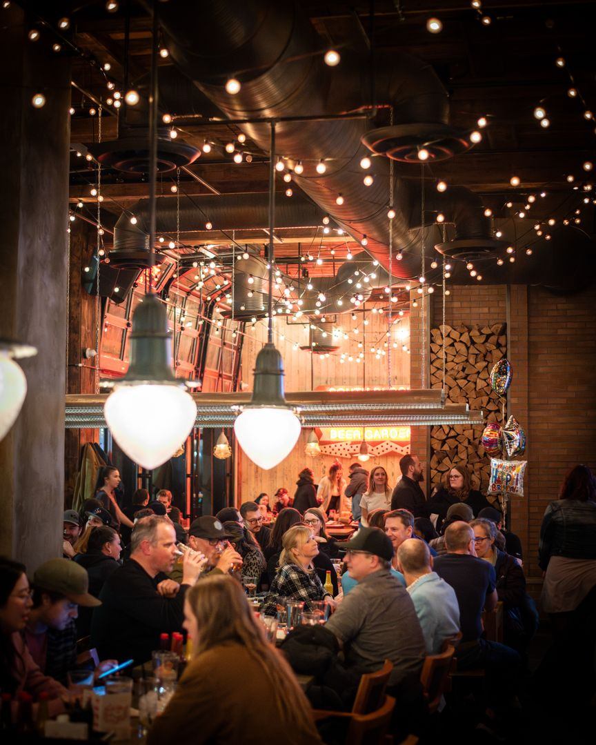 Crowded restaurant interior with string lights and guests dining.