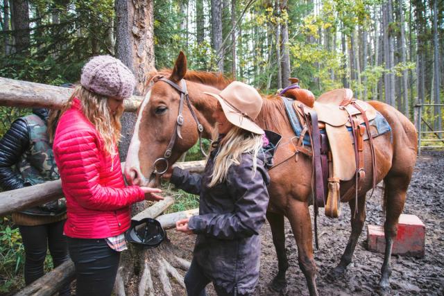 People standing with a horse in a corral at Banff Trail Riders.