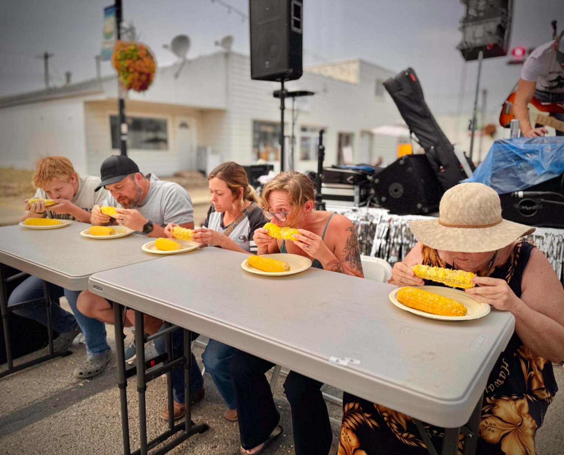 Participants seated at a table take part in a corn‑eating contest during the Harvest Moon Festival.