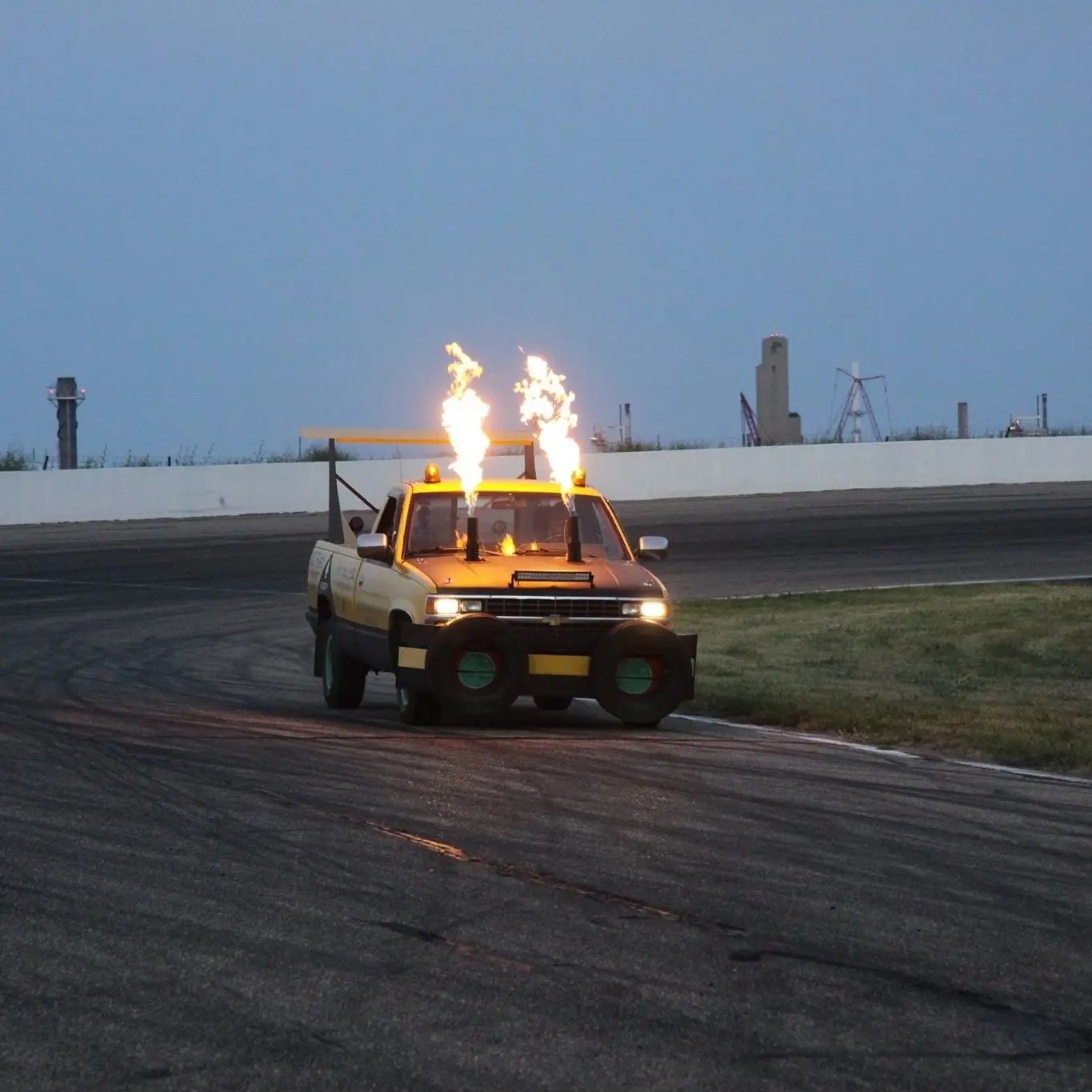A truck on the raceway with flame stacks coming out of the bonnet