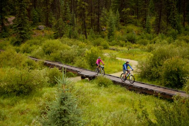 Couple mountain biking in the Valley of Five Lakes in Jasper Provincial Park.