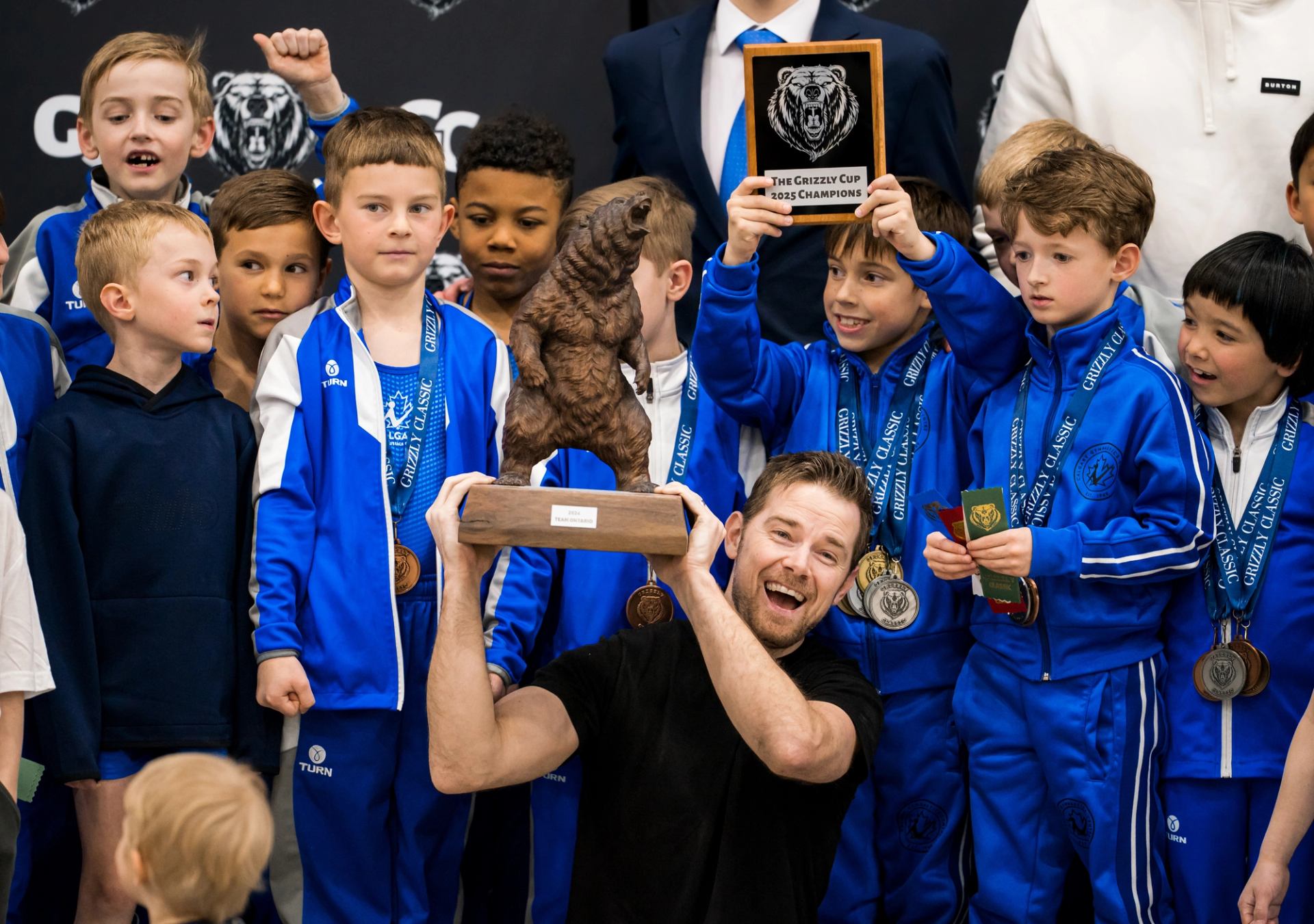 Gymnastics team celebrating with medals and trophies at an awards ceremony.