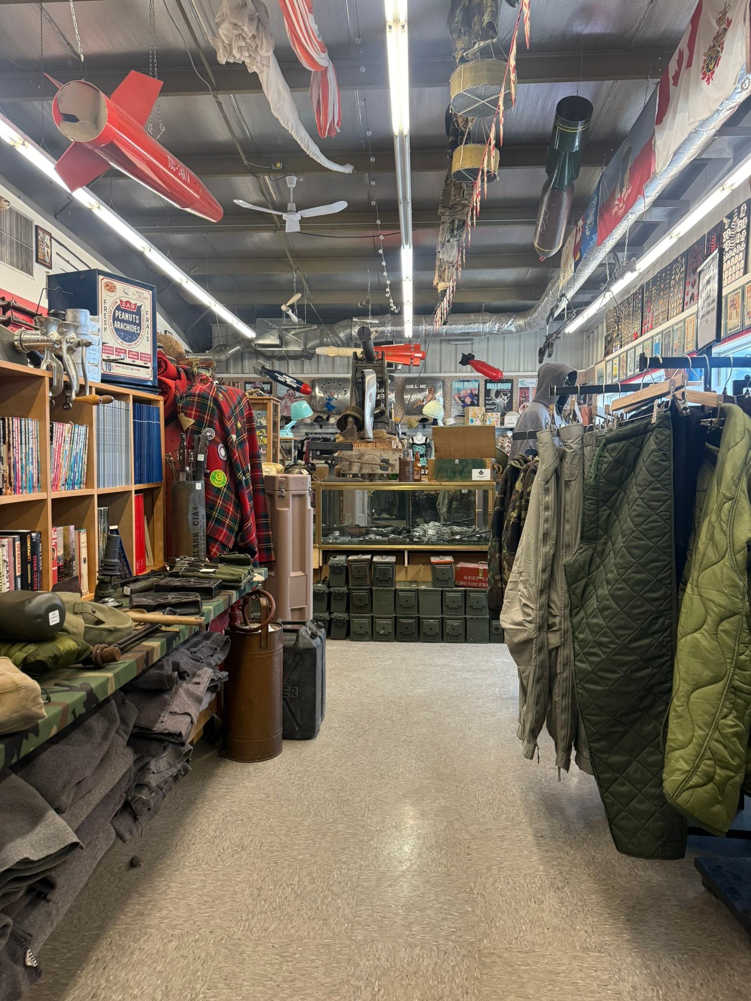 Crown Surplus Store inside view with jackets, surplus gear, tools, books, and hanging displays under bright lighting.