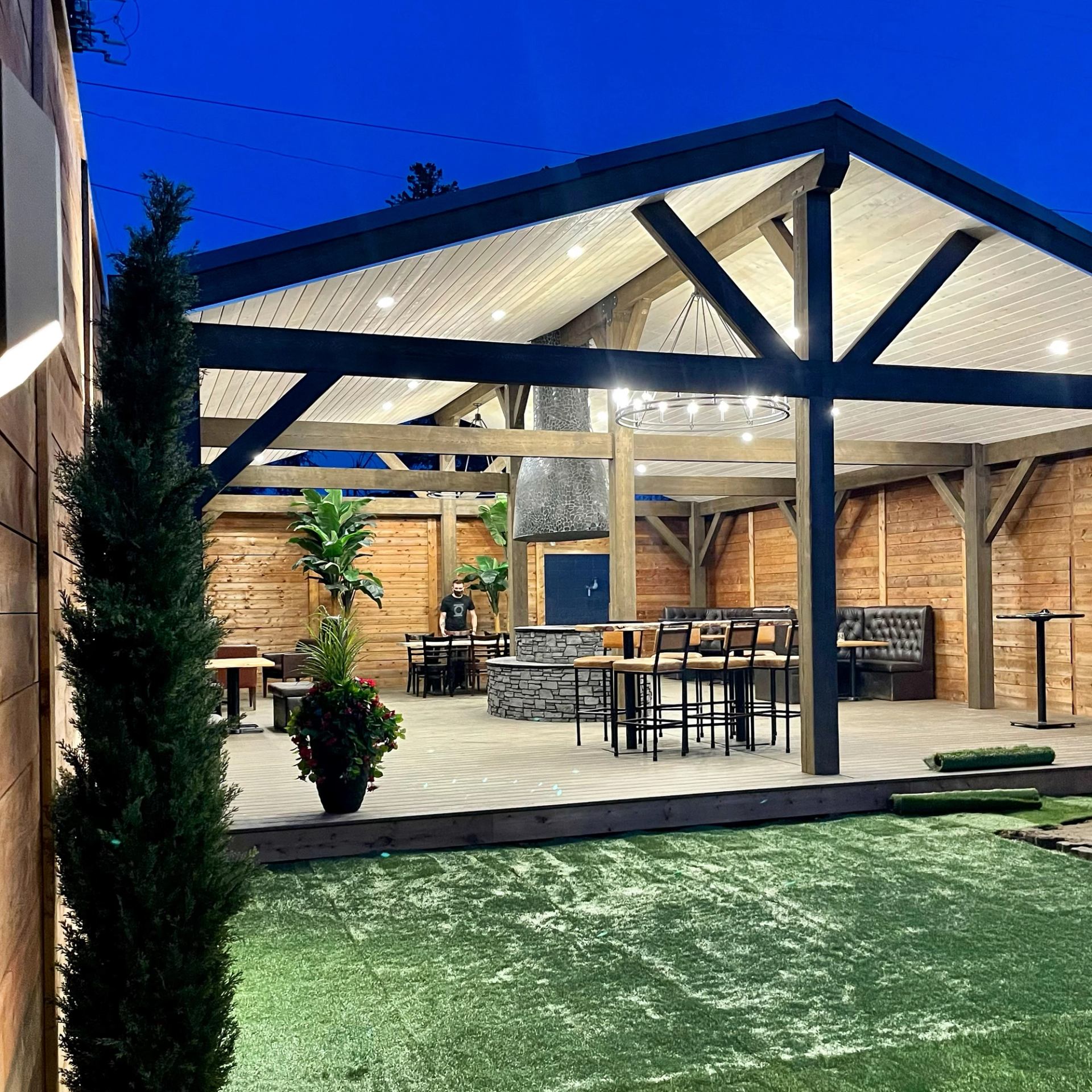 Patio with wooden beams, string lights, and seating at dusk.