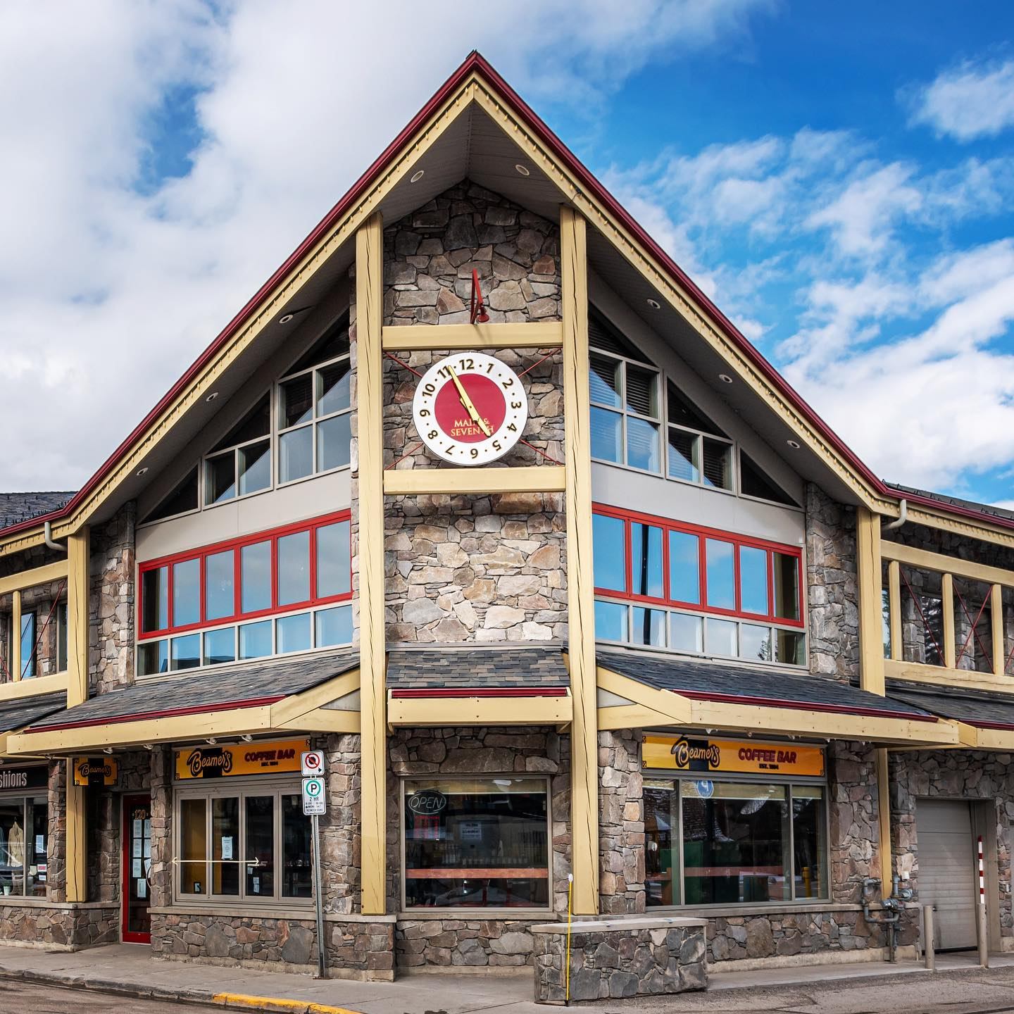 Stone building with large clock and Beamer’s Coffee Bar storefront under blue sky.