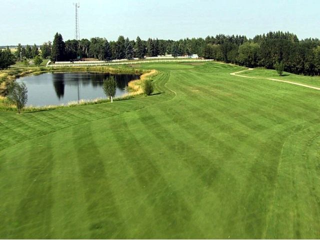 Striped fairway with pond, trees, and blue sky at Gleniffer Lake Golf Course.