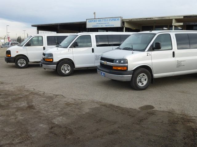 A line up of white passenger vans at the airport.