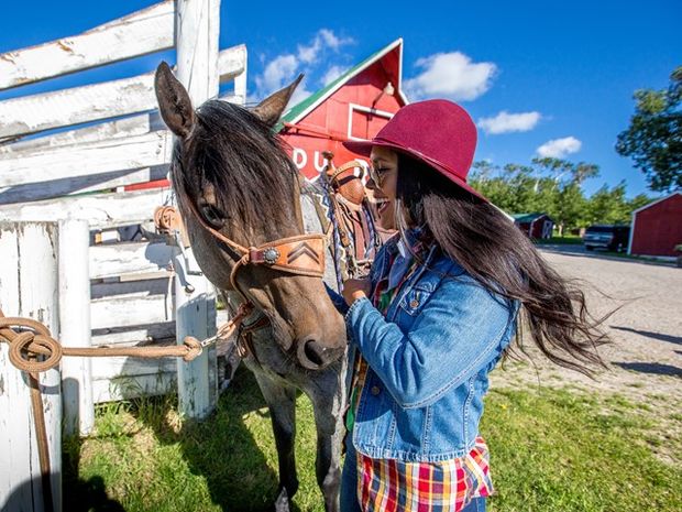 A woman pets a horse before horseback riding with Centre Peak High Country Adventures in the Crowsnest Pass.