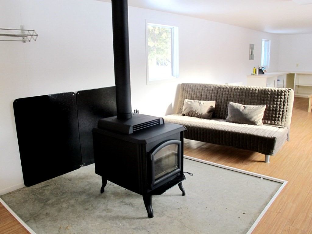Wood-burning stove and wicker sofa in cozy room with natural light at Medicine Lodge.