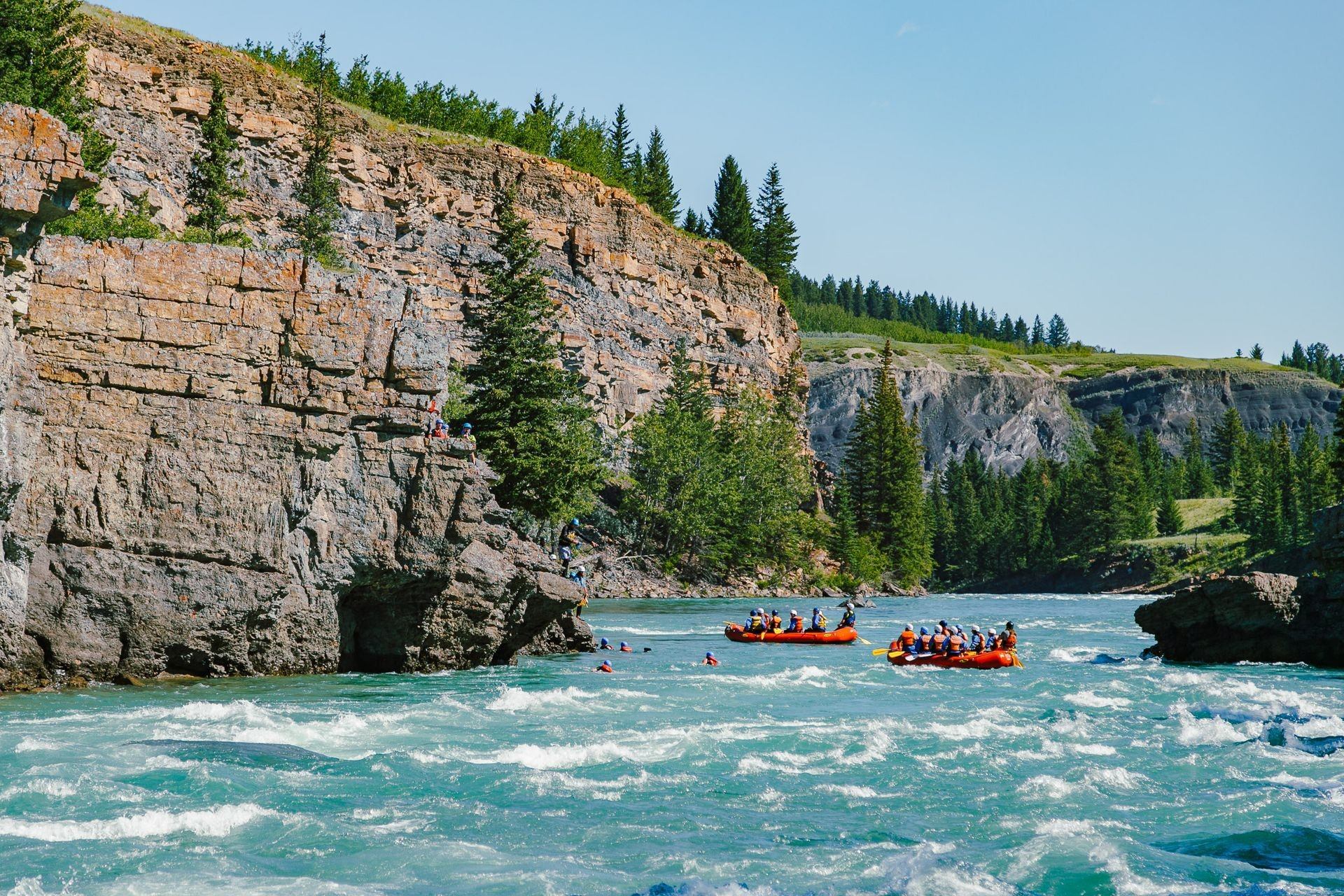 A serene view of the Canadian Rockies with a whitecapped river flowing through granite banks..