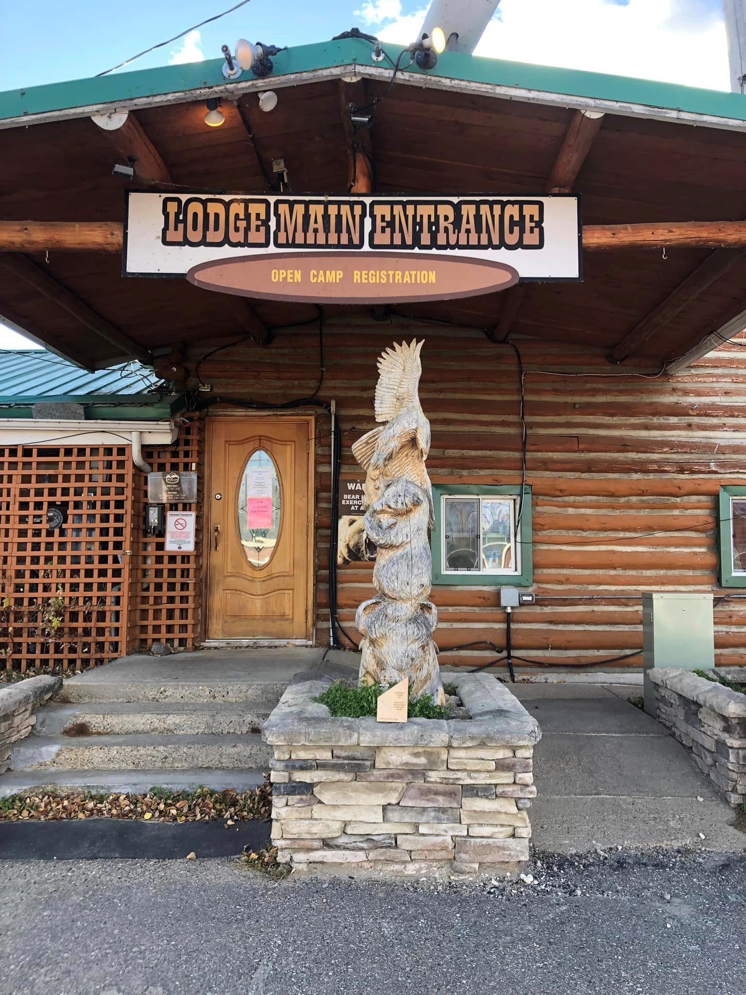 Row of log cabins with porches and a picnic table on a grassy lawn.