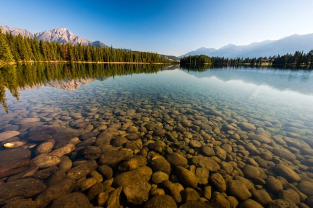 Scenic view of submerged rocks in the clear waters of Lac Beauvert with Pyramid Mountain in Jasper National Park.