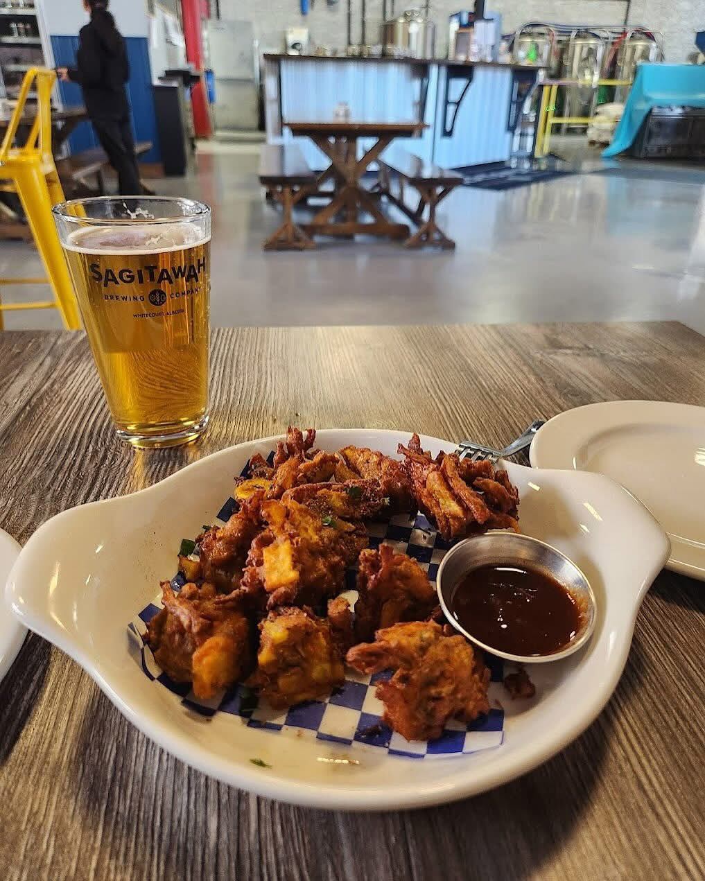 Beer glass with Sagitawah Brewing Company label and a plate of wings and dipping sauce.