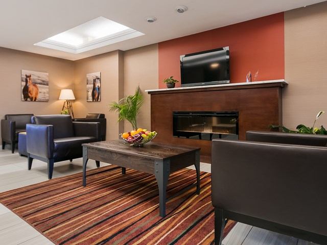 Lounge area with fireplace, TV, seating, and coffee table at Best Western Plus Red Deer.