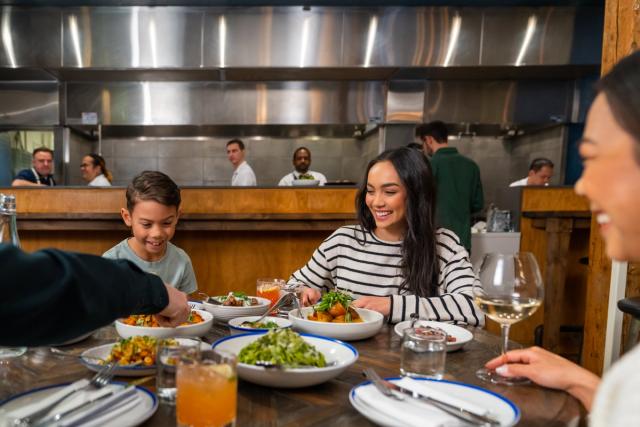 Family enjoys a dinner while the chefs work in the background at Ten Foot Henry.