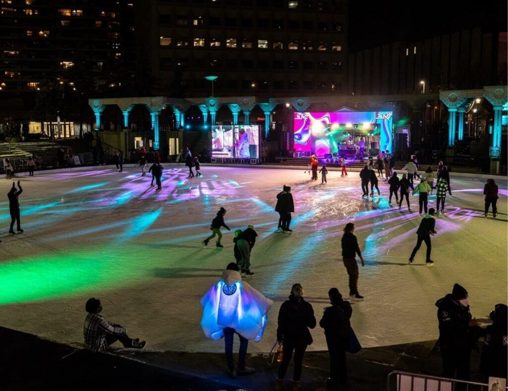 People skating on rink with colorful lights and music.