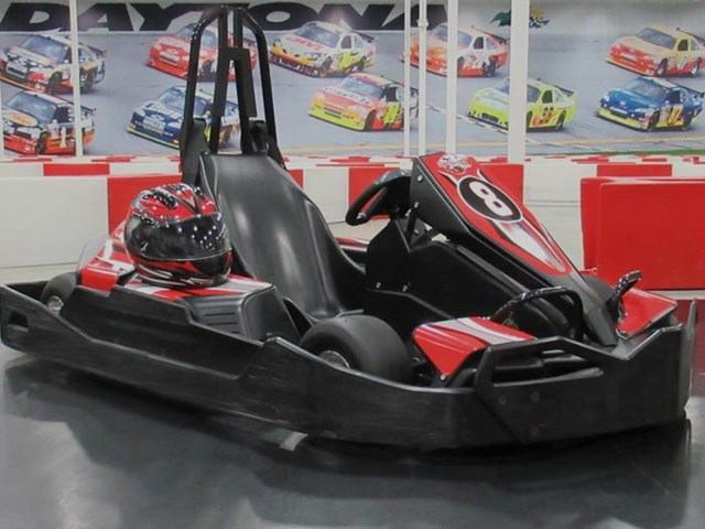 Black and red go-kart with helmet on seat at SPEEDERS Indoor Prokarts.