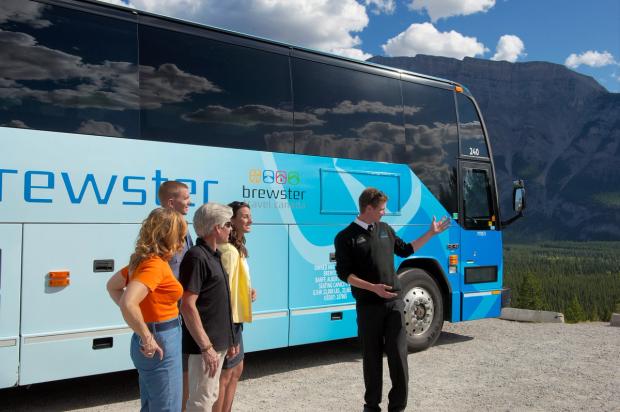 Tour guide with a group in front of a Brewster Travel tour bus in Banff National Park.