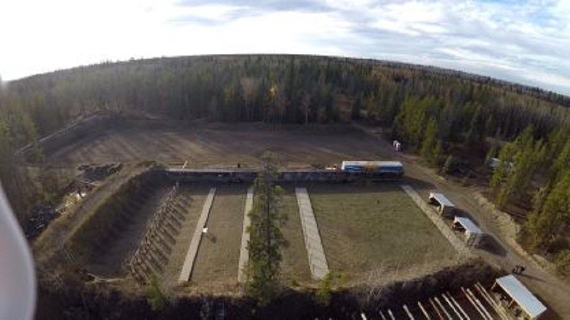 Forest-surrounded shooting range with covered areas and distant targets.