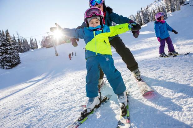 A young child with mom, learning to ski at Sunshine Village in Banff National Park.