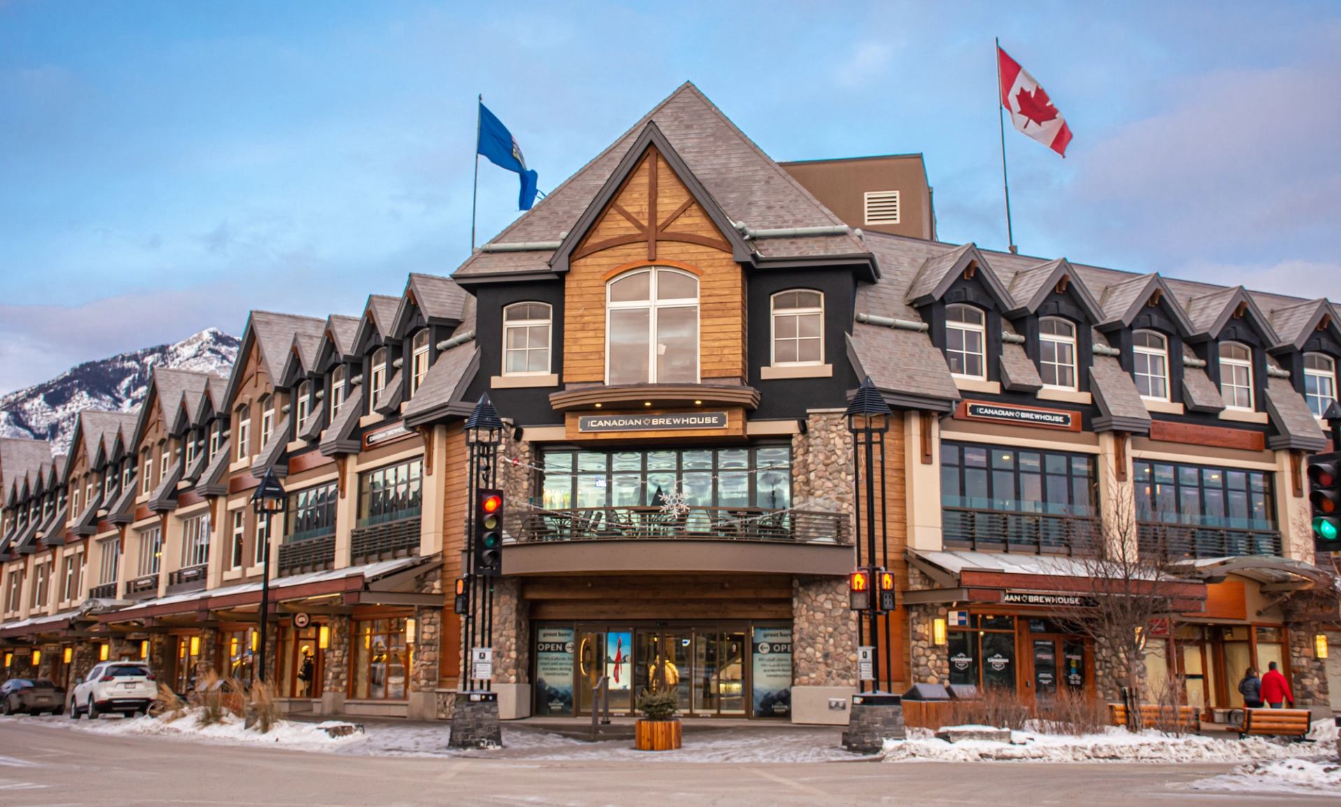 Canadian Brewhouse building with flags and snowy mountains in the background
