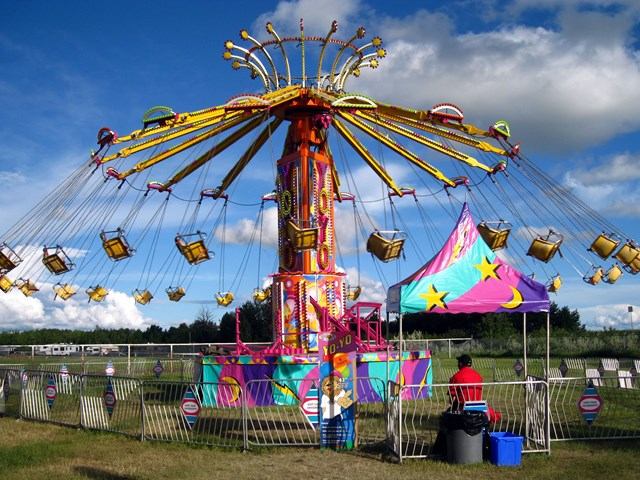 Brightly coloured swing ride at the Wainwright Stampede with empty seats blowing in the wind.