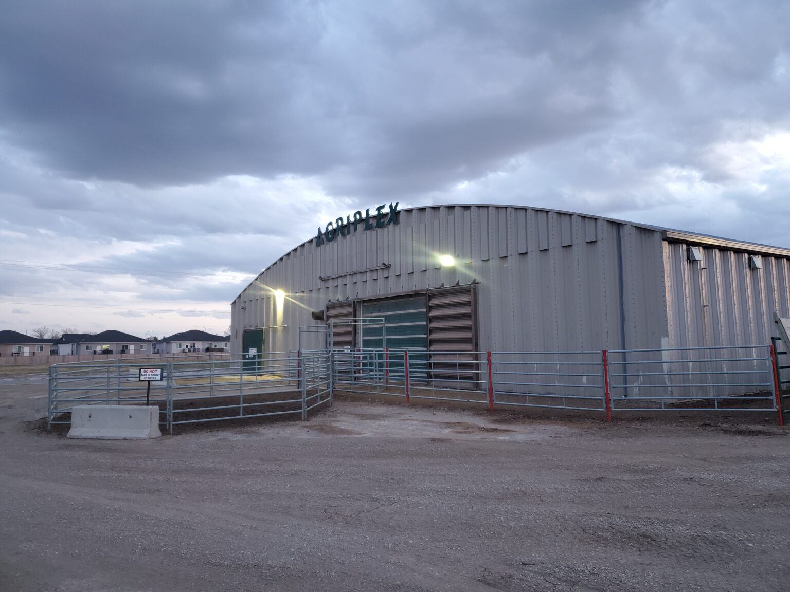 Claresholm Agriplex arena building is surrounded by fencing, gates, and open prairie community grounds.