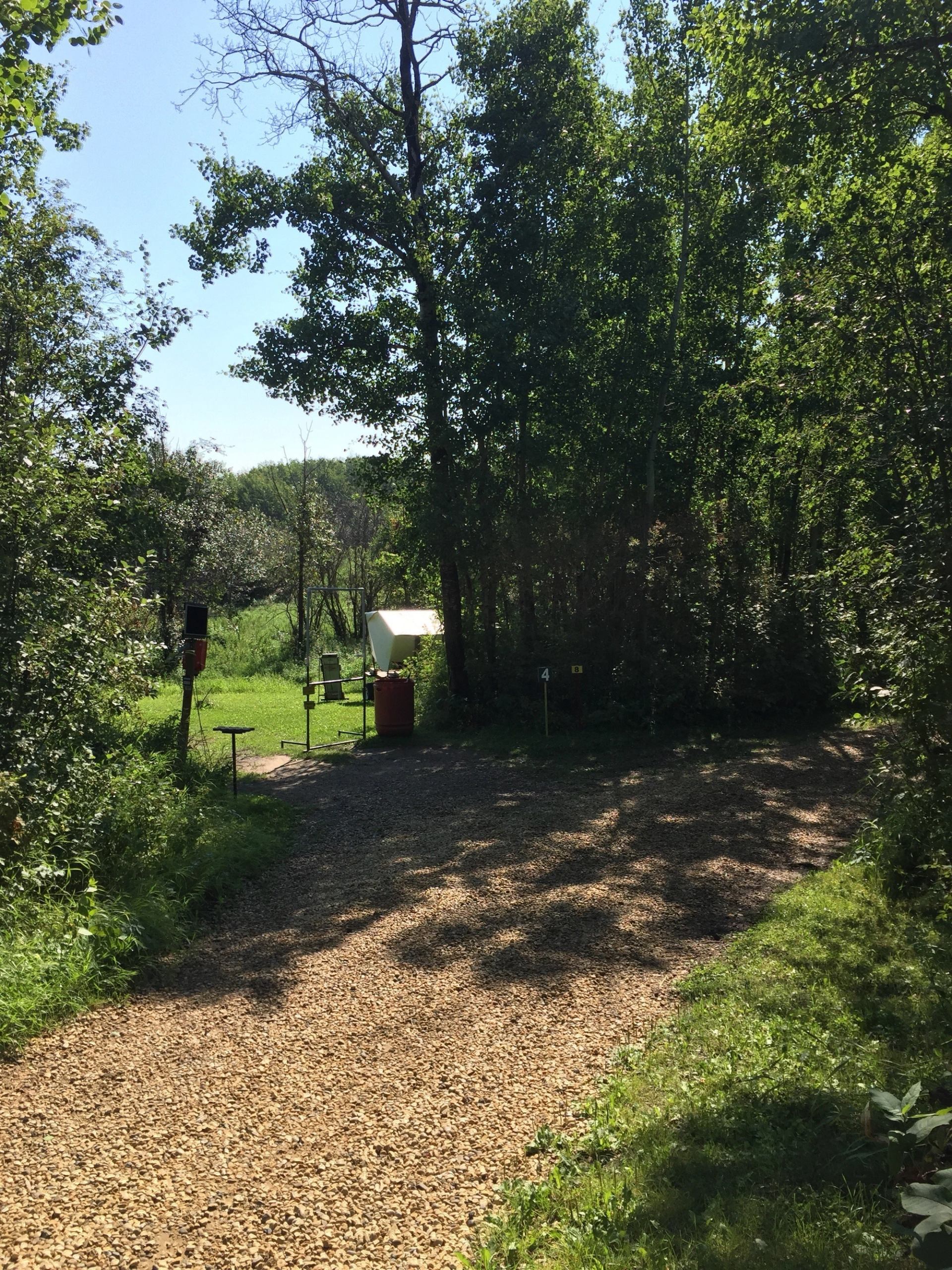 Outdoor shooting station with gravel lane, trees, and numbered targets at Beaverhill Sporting Clays.