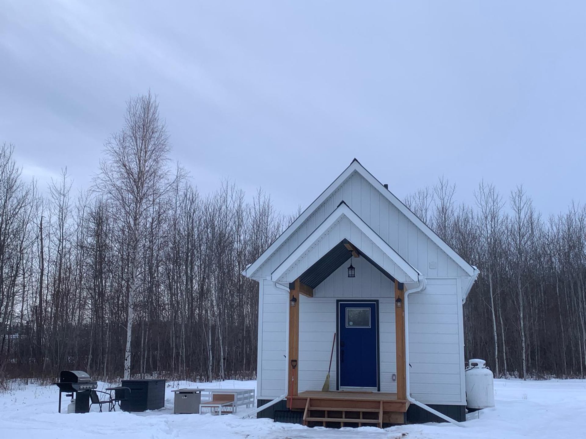 White cabin in snowy woods at Wildly Eweneek Cabins.