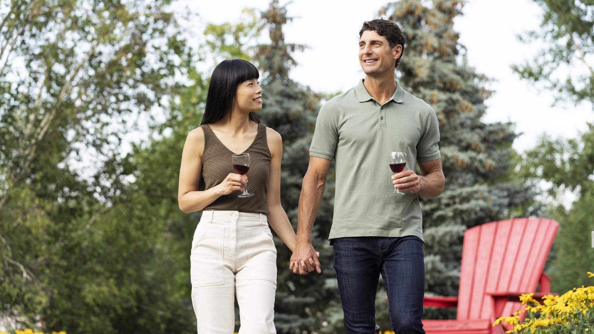 Two people holding hands drinking wine.
