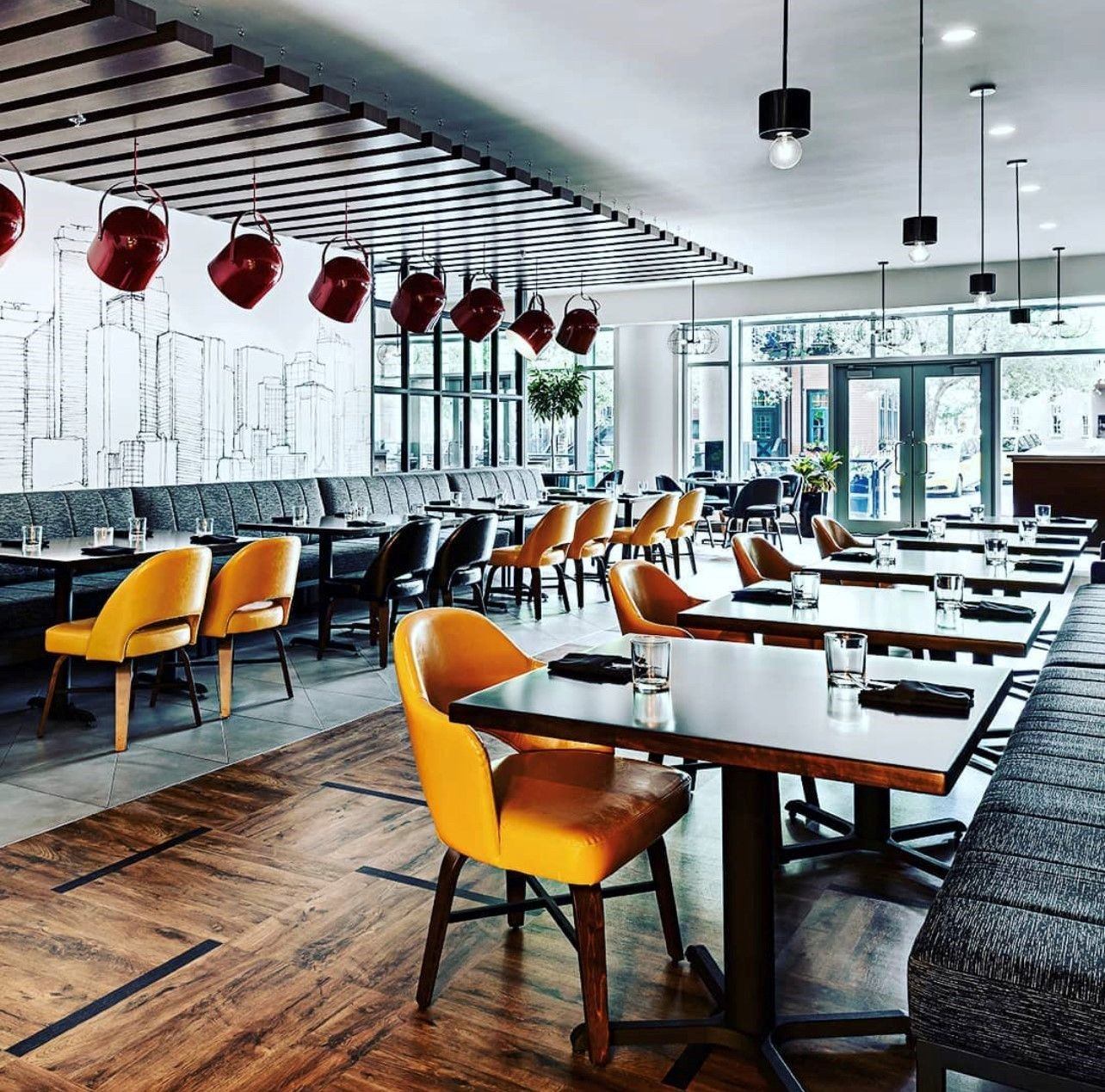 Modern restaurant interior with orange chairs and red ceiling lights.
