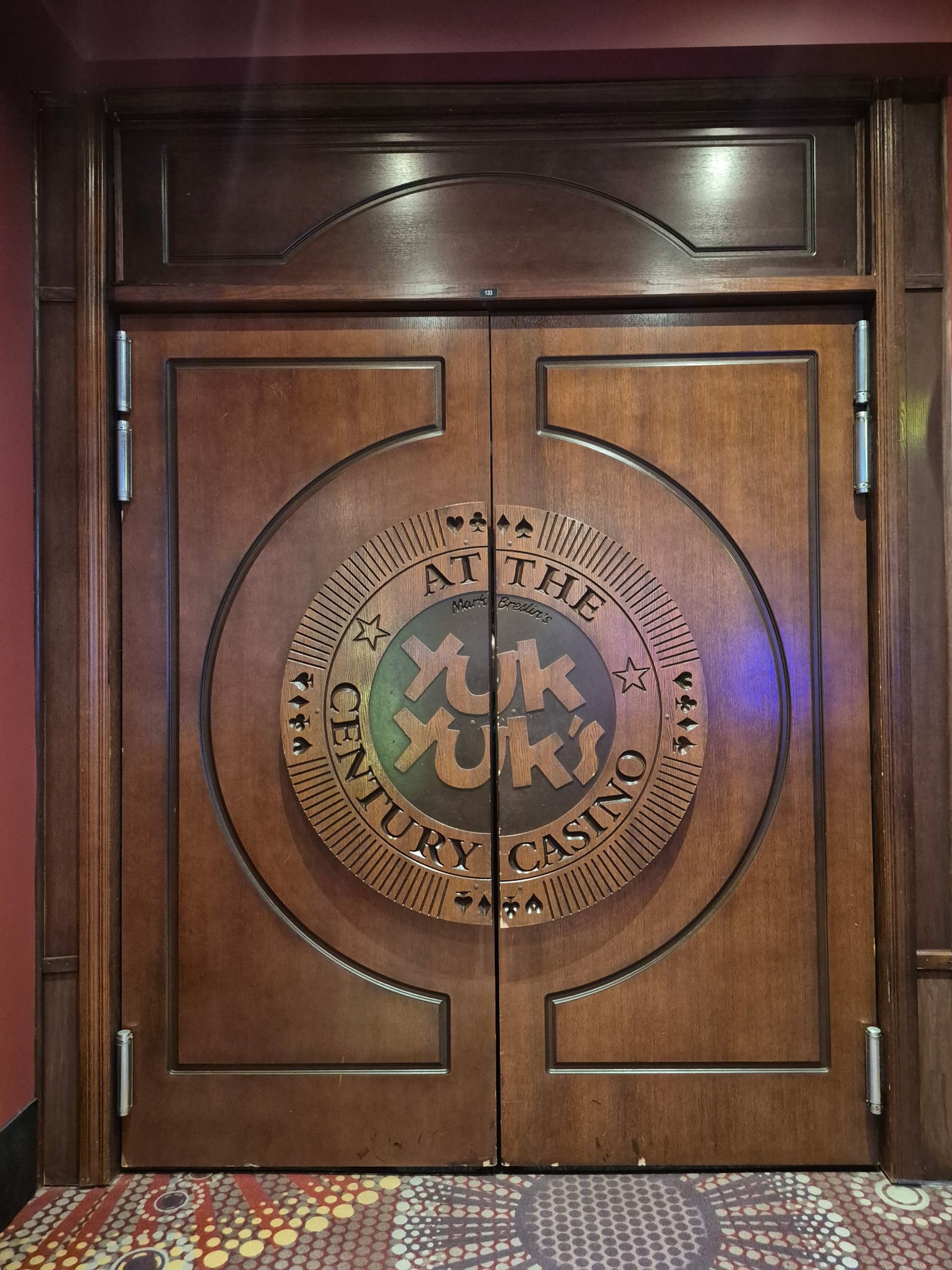 Wooden doors with Yuk Yuk's logo at Century Casino entrance.