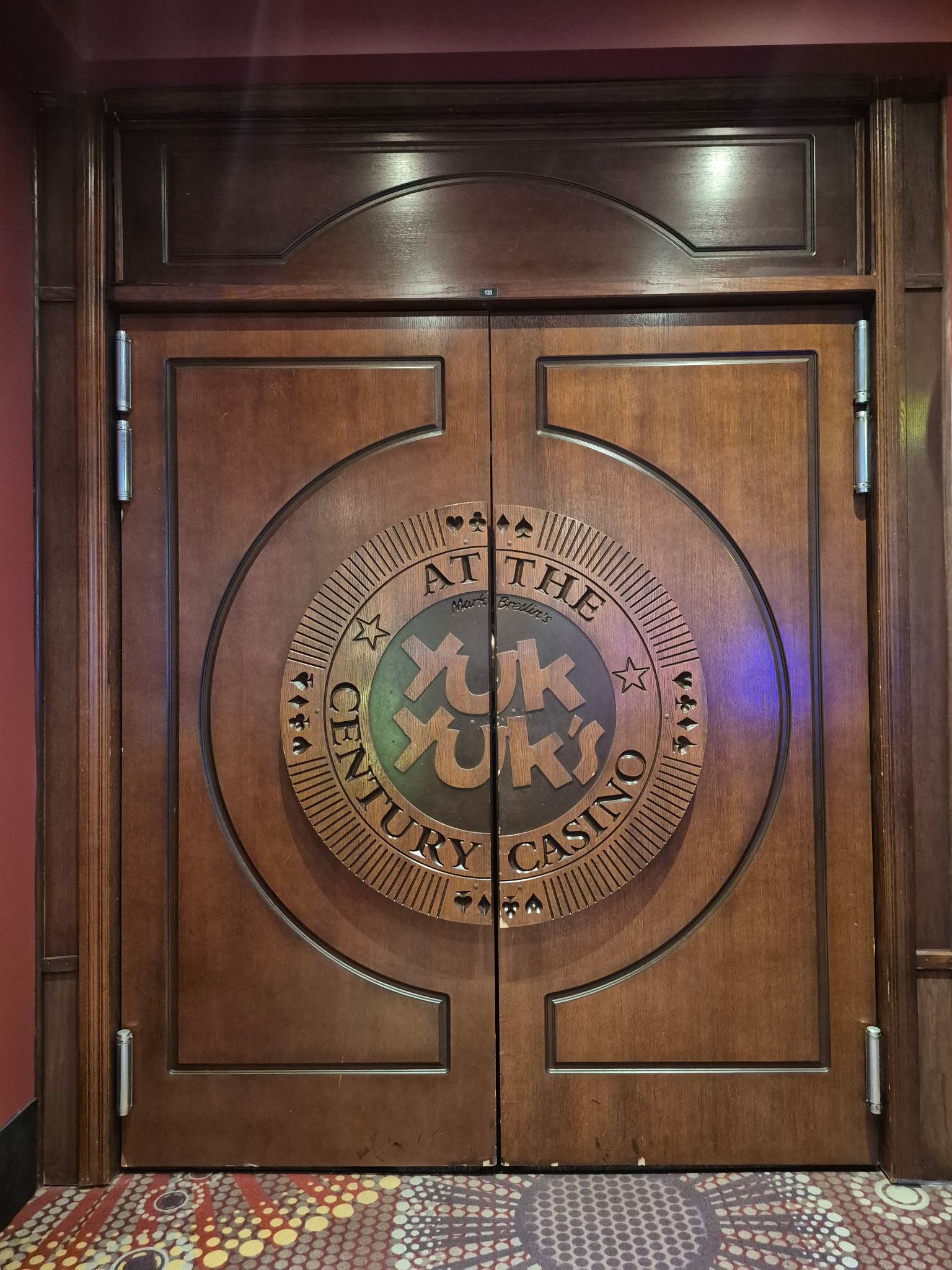 Wooden doors with Yuk Yuk's logo at Century Casino entrance.